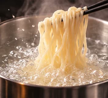 沸騰した湯で茹でられる平打ちの生麺